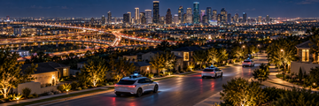 Aerial night view of Houston with electric robotaxis driving through illuminated streets and suburban neighborhoods