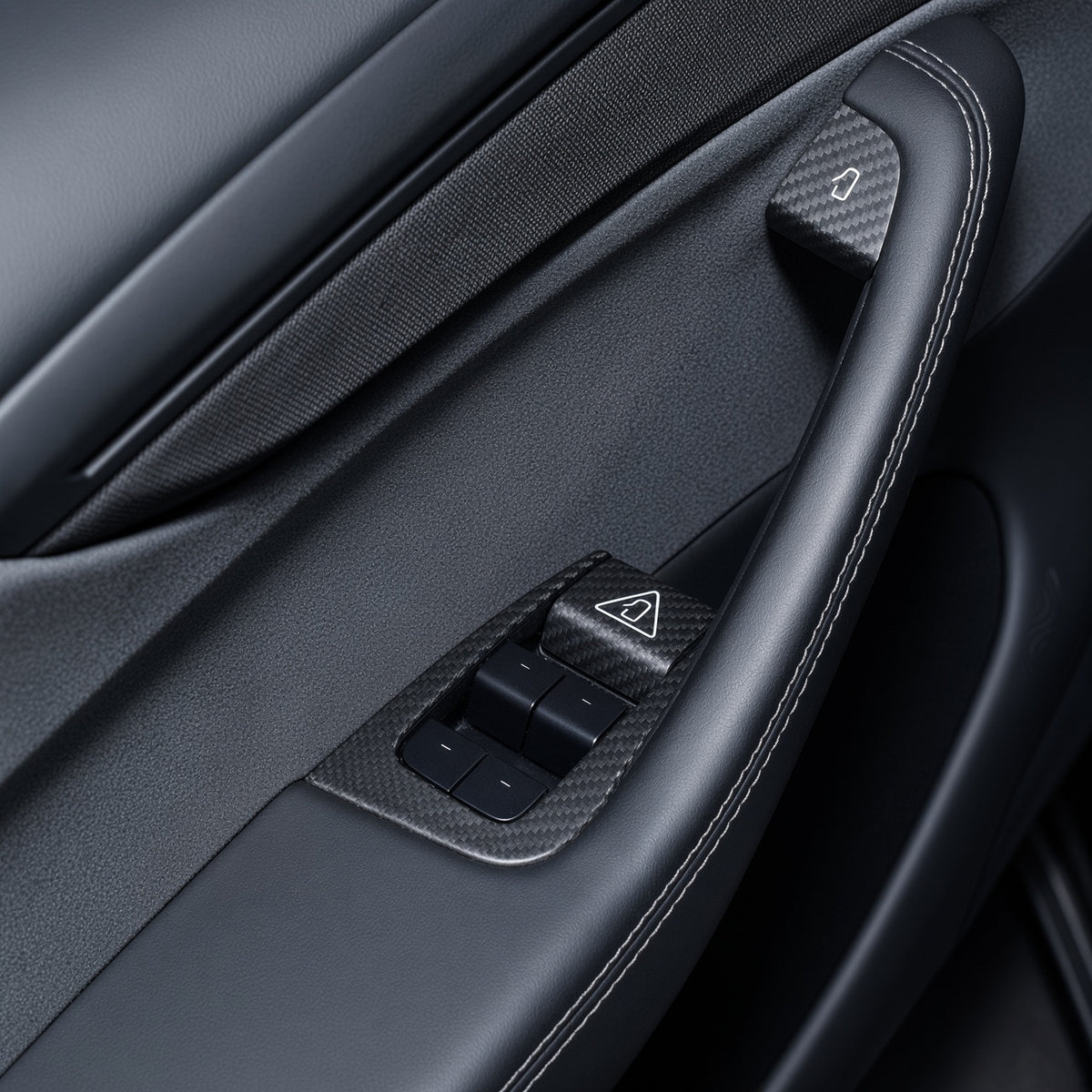Black door panel with carbon-weave trim around four window switches and covers at the door-release controls.