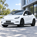 Parked white Model Y showing a black bracket at the front bumper plate position