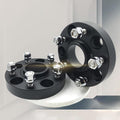 Two TESERY forged wheel spacers displayed on a pedestal, showing black bodies, center lips and silver hardware.
